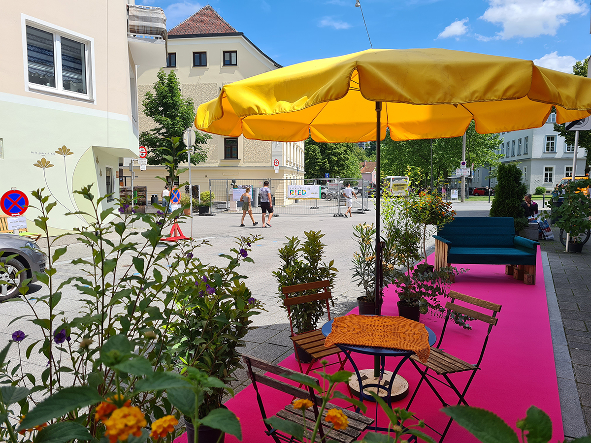 Gartenmöbel und selbst gestaltete Möbel auf rosa Teppich im öffentlichen Raum